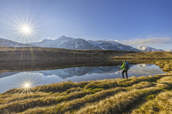 A man observes sunrise at Lago degli Andossi, Montespluga, Madesimo, Sondrio, Valle Spluga, Lombardy, Italy, Southern Europe