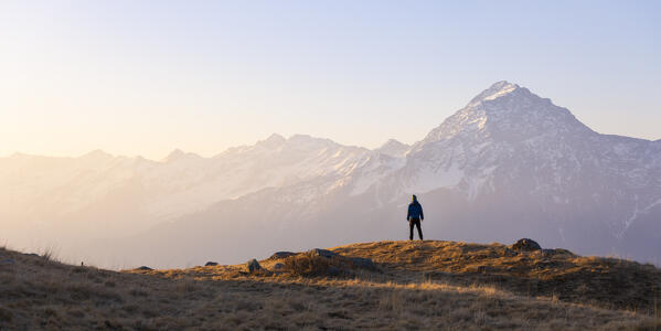 A trekker observes Monte Legnone at sunrise from Montemezzo, Alto Lario, Montemezzo, Como, Lombardy, Italy, Southern Europe 