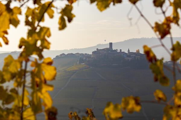 Castiglione Falletto framed by colors with vineyards at sunset during autumn and a balloon, Cuneo, Langhe and Roero, Piedmont, Italy, Southern Europe