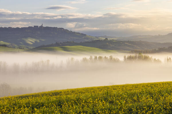 View of San Quirico D'Orcia and hills with fog in Val D'Orcia at sunrise, San Quirico d'Orcia, Siena, Tuscany, Italy, Southern Europe