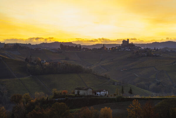 Serralunga D’Alba and its castle with vineyards at sunrise in backlight during autumn, Cuneo, Langhe and Roero, Piedmont, Italy, Southern Europe
