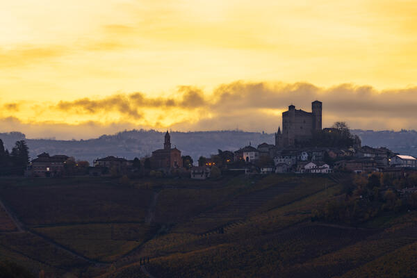 Serralunga D’Alba and its castle with vineyards at sunrise in backlight during autumn, Cuneo, Langhe and Roero, Piedmont, Italy, Southern Europe