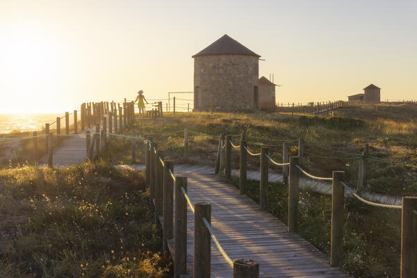 A tourist observes ocean around Apulia Windmills at sunset, Apulia, Esposende, Braga, Norte, Portugal, Iberian Peninsula, Western Europe