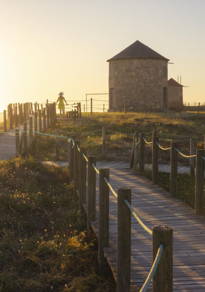 A tourist observes ocean around Apulia Windmills at sunset, Apulia, Esposende, Braga, Norte, Portugal, Iberian Peninsula, Western Europe
