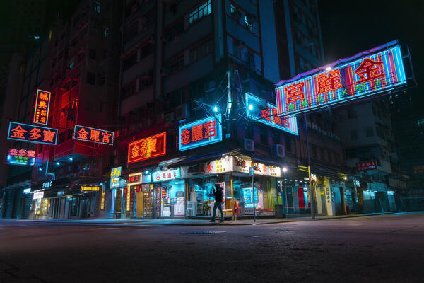 a person walks past neon lit shops during night, Mong Kok, Hong Kong, China, Asia