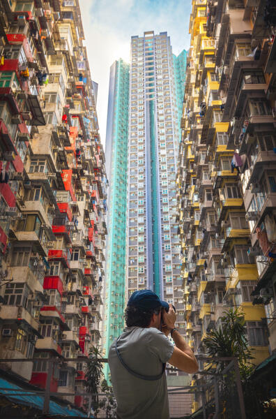 A tourist takes a photo of Monster Buildings during daytime, Quarry Bay. Hong Kong, China, Asia