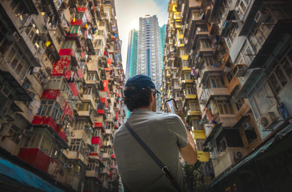 A tourist takes a photo with his phone of Monster Buildings during daytime, Quarry Bay. Hong Kong, China, Asia