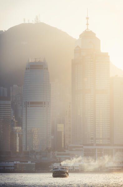 A boat sails in front of cityscape of Hong Kong during sunset, Tsim Sha Tsui, Kowloon, Hong Kong, China, Asia