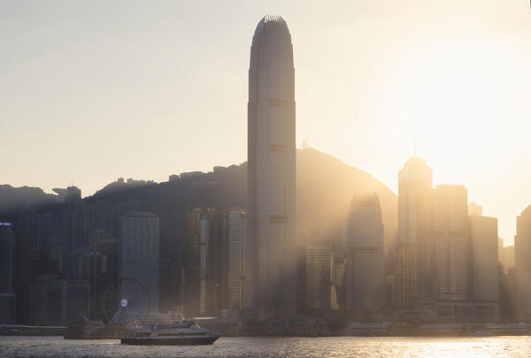 A boat sails in front of cityscape of Hong Kong during sunset, Tsim Sha Tsui, Kowloon, Hong Kong, China, Asia