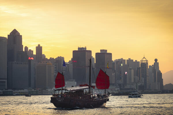 Ancient Dunkling boat sails in front of cityscape of Hong Kong during sunset, Tsim Sha Tsui, Kowloon, Hong Kong, China, Asia
