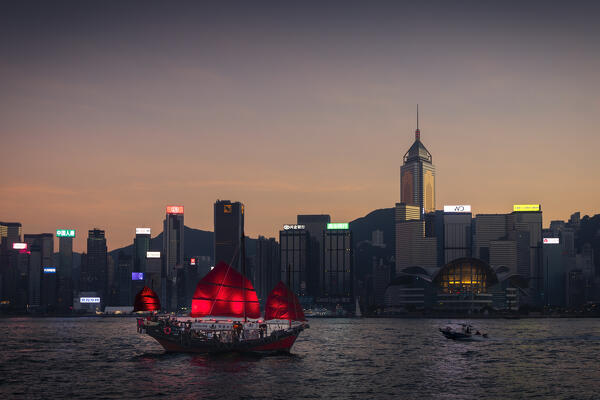 Ancient Dunkling boat sails in front of cityscape of Hong Kong during sunset, Tsim Sha Tsui, Kowloon, Hong Kong, China, Asia