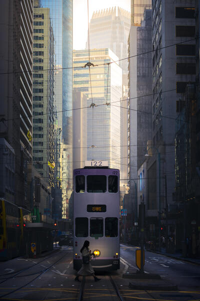 A woman crosses the tracks of the tram in Western Market during sunrise, Sheung Wan, Hong Kong island, Hong Kong, China, Asia