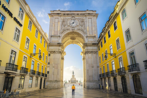 A tourist observes the iconic Arco da Rua Augusta during sunrise, Baixa, Lisbon, Portugal, Iberian peninsula, Western Europe