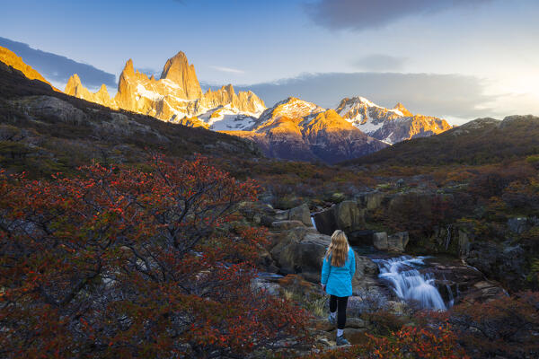 A tourist observes Escondida waterfall and Fitz Roy mountain in the background during sunrise, El Chalten, Parque Nacional Los Glaciares, Santa Cruz, Patagonia Argentina, Argentina, South America