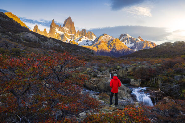 A tourist observes Escondida waterfall and Fitz Roy mountain in the background during sunrise, El Chalten, Parque Nacional Los Glaciares, Santa Cruz, Patagonia Argentina, Argentina, South America