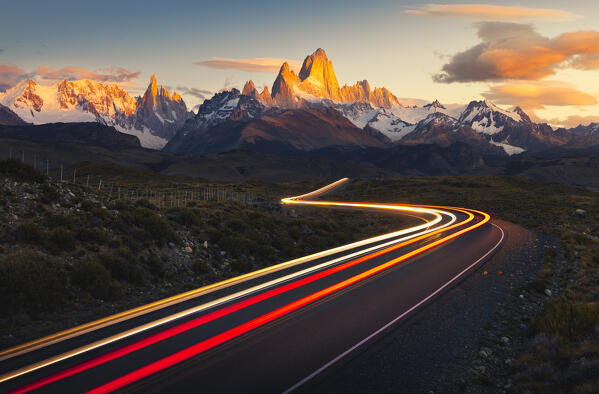 Trails of car lights along the main road to el Chalten with Fitz Roy in the background during sunrise, El Chalten, Parque Nacional Los Glaciares, Santa Cruz, Patagonia Argentina, Argentina, South America
