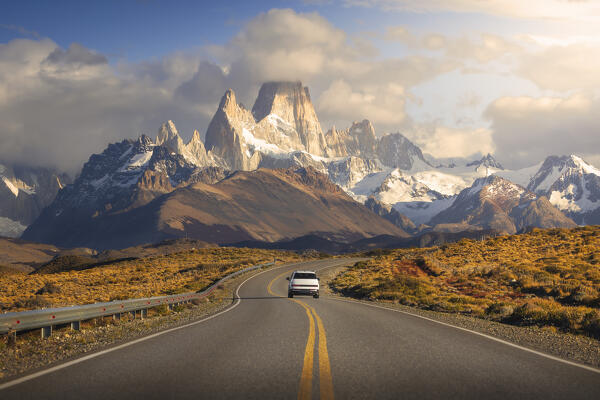 A car travels along the main road to el Chalten with Fitz Roy in the background during sunrise, El Chalten, Parque Nacional Los Glaciares, Santa Cruz, Patagonia Argentina, Argentina, South America