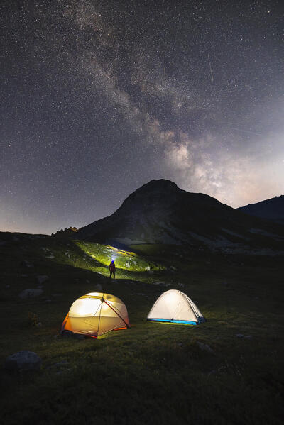 A hiker onserves Le Rocher Blanc under Milkyway during a starry night, Provence Alps Cote d’Azur, Haute Alps, Vallee Etroite, France, Europe (MR)