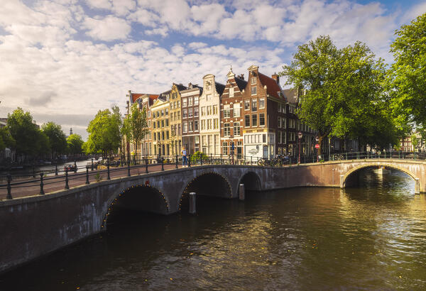 A tourist observes canals of Amsterdam from a bridge during sunset in summer, Amsterdam, Centrum, Stadsdeel, Grachtengordel, Netherlands, North Holland, Western Europe