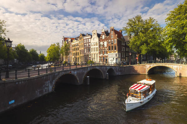 Typical houses and canals with a boat in Amsterdam during summer sunset, Amsterdam, Centrum, Stadsdeel, Grachtengordel, Netherlands, North Holland, Western Europe