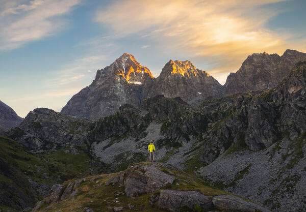 A trekker in front of Monviso over Fiorenza Lake observes sunset, Crissolo, Cuneo, Piedmont, Italy, Southern Europe