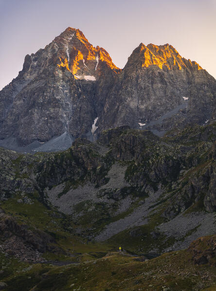 Aerial view of a trekker in front of Monviso over Fiorenza Lake observes sunset, Crissolo, Cuneo, Piedmont, Italy, Southern Europe