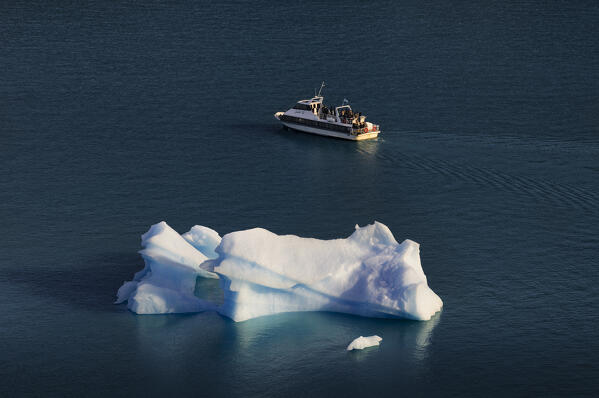 A boat near a big block of ice in the lagoon in front of of Perito Moreno glacier, Parque Nacional Los Glaciares, El Calafate, Santa Cruz, chilean antarctica region, Patagonia Argentina, Argentina, South America