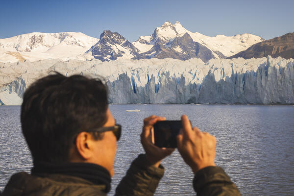 A tourist photographs glacier front of Perito Moreno and mountains from a boat, Parque Nacional Los Glaciares, El Calafate, Santa Cruz, chilean antarctica region, Patagonia Argentina, Argentina, South America