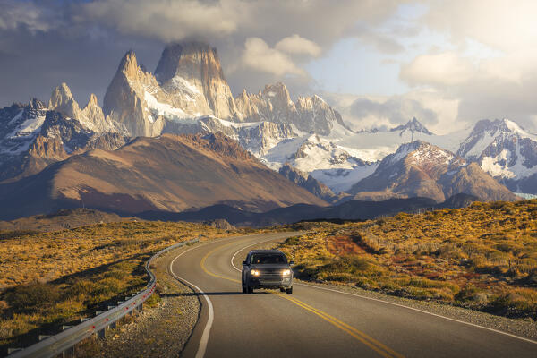 A car travels along the main road to el Chalten with Fitz Roy in the background during sunrise, El Chalten, Parque Nacional Los Glaciares, Santa Cruz, Patagonia Argentina, Argentina, South America
