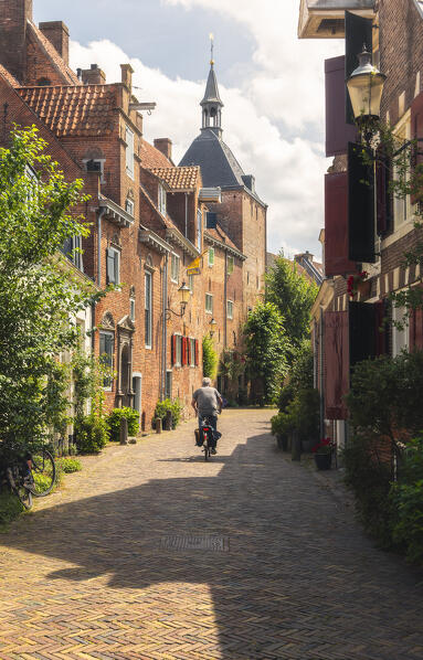 A cyclist pedals along the road in front of Dieventoren in Amersfoort during summer, Amersfoort, Netherlands, Utrecht, Western Europe