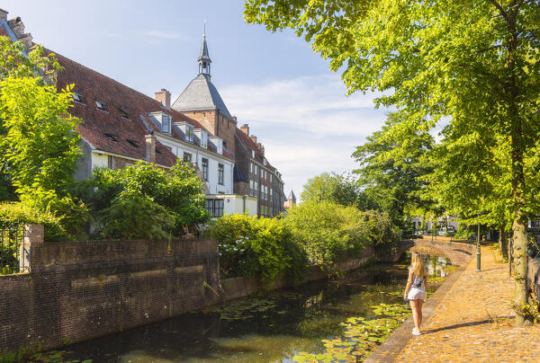 A tourist observes Dieventoren along the canal in Amersfoort during summer, Amersfoort, Netherlands, Utrecht, Western Europe (MR)