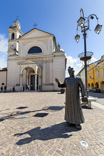 Brescello: the statue of Don Camillo and the Santa Maria Nascente church. The village is famous for the films of Don Camillo and Peppone. Reggio Emilia province, Emilia Romagna, Italy, Europe.