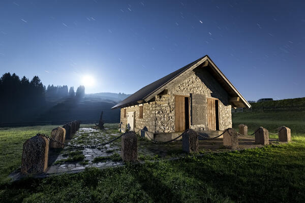 Malga Zonta, monument to the Italian Resistance, on a full moon night. Coe pass, Folgaria, Alpe Cimbra, Trentino, Italy.