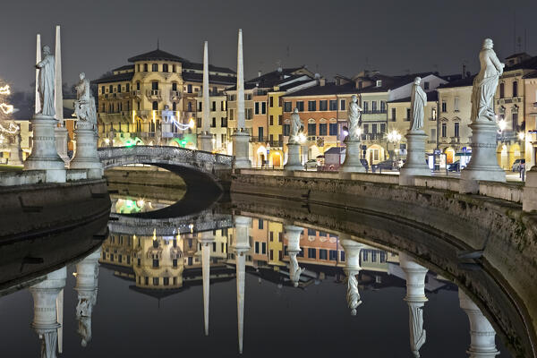 Bridge and sculptures of Prato della Valle with the Sacerdoti palace reflected in the canal. Padua, Veneto, Italy.
