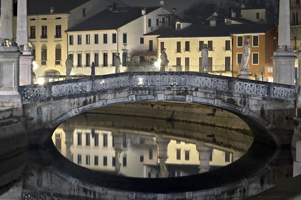 Bridge and sculptures of Prato della Valle with the Sacerdoti palace reflected in the canal. Padua, Veneto, Italy.