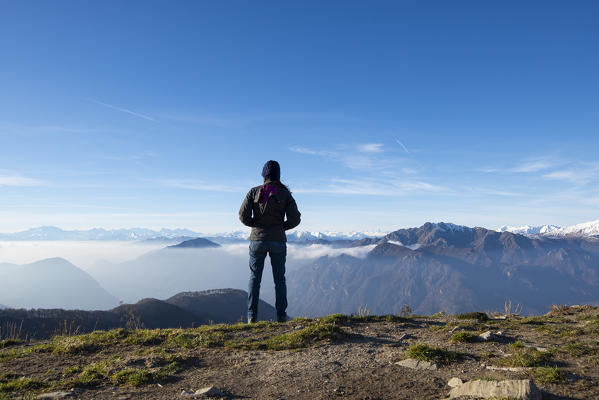Alpe di Lenno, Como province, Lombardy, Italy, Europe. Girl standing and looking at the Alps in the distance