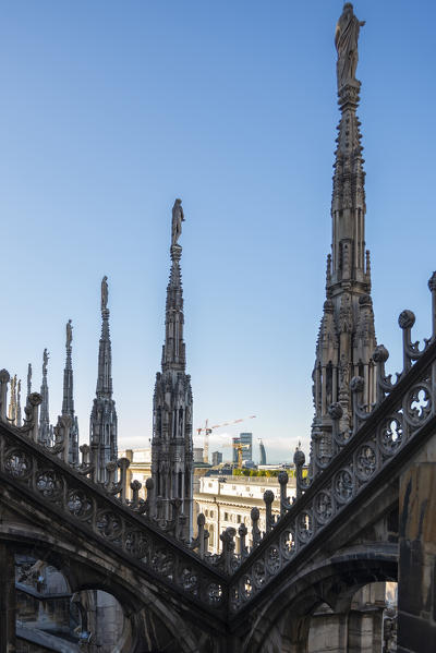 Milan, Lombardy, Italy, Europe. Milan's skyline seen from behind the spiers of Milan cathedral