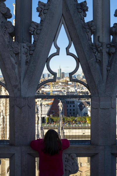 Milan, Lombardy, Italy, Europe. Little girl is watching Porta Nuova's skyscrapers from the rooftop of Milano Cathedral