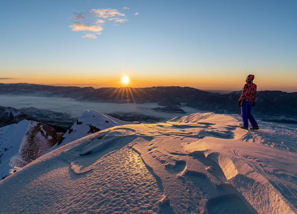 Hiker enjoys the sunrise on the top of Col Cesta, Feltre, Belluno province, Italy, Europe