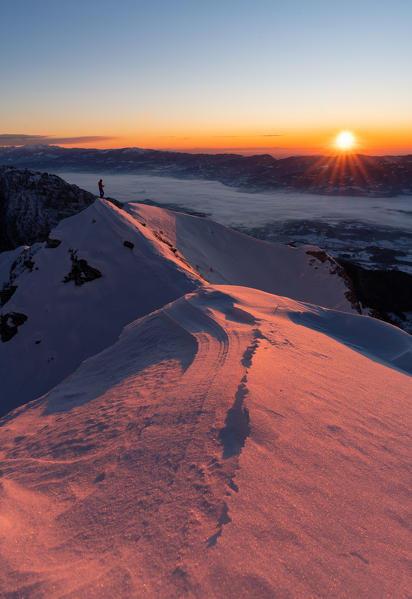 Hiker enjoys the sunrise on the top of Col Cesta, Feltre, Belluno province, Italy, Europe