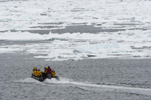 Tourists on zodiacs exploring  the polar ice cap, at 81* north of Spitsbergen.