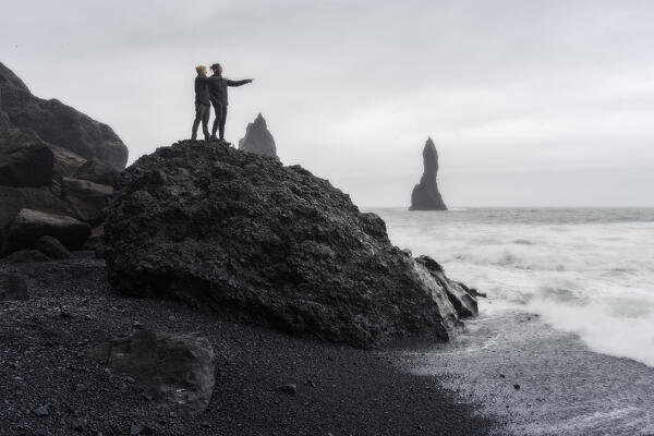 Tourist looking the horizon on a massive rock at Reynisfjara Beach: Southern Iceland, Europe