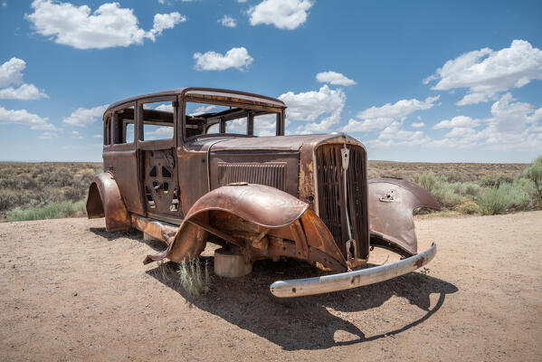 Next to the Interstate 40, on the Old Route 66 path, this old car's shell is a landmark of the West conquest; Petrified Forest and Painted Desert National Park, Arizona, United States of America