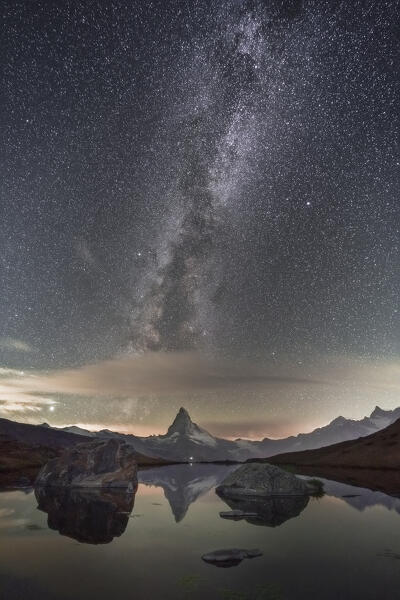 Milky Way with iconic Matterhorn, with a small lake in background, during a night in august, Zermatt, Switzerland