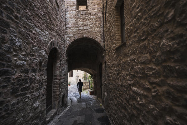 A young man is walking on the street of Spello, Perugia Province, Umbria, Italy,Europe