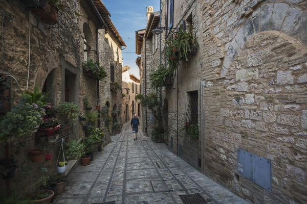 A young man is walking on the street of Spello, Perugia Province, Umbria, Italy,Europe