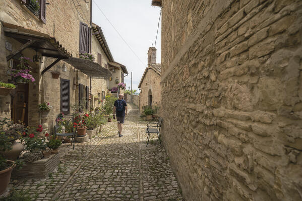 A young man is walking down the street of Montefalco. Montefalco, Perugia province, Umbria, Italy, Europe.