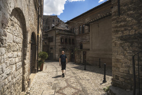 A young man is walking down the street of Narni. 
Narni, Terni province, Umbria, Italy, Europe.