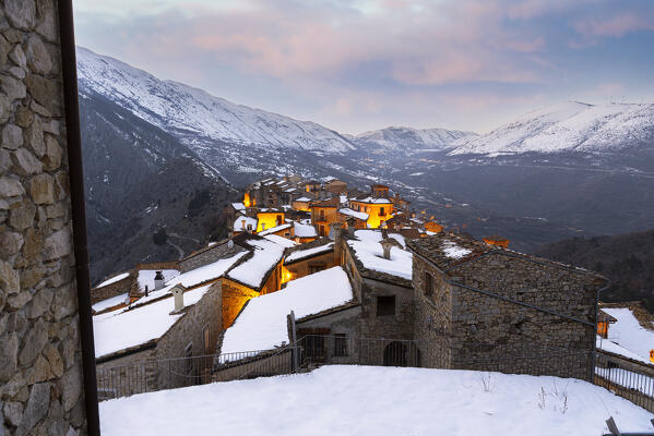 Winter sunset in the mountain village of Castrovalva with snow covered and snowy mountains in the background, L’Aquila province, Abruzzo, Italy