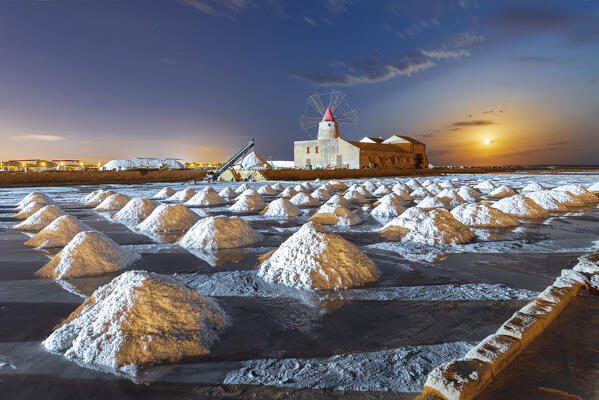 Windmill night view with full moon and salt pyramids at the salt flats, saline dello Stagnone, Marsala, Trapani province, Sicily, Italy